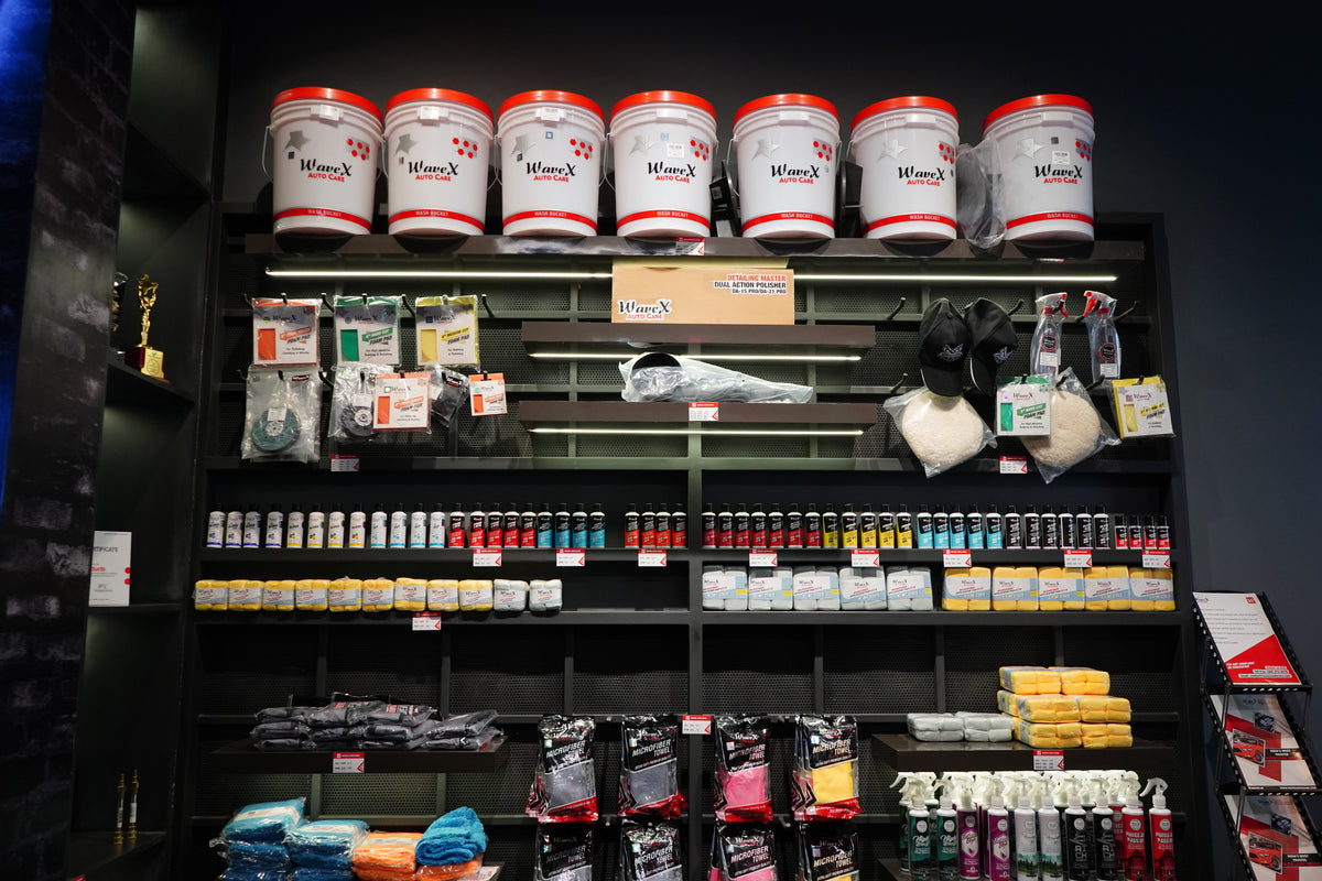 A complete row of red-lid Wavex wash buckets above car-care products and detailing accessories